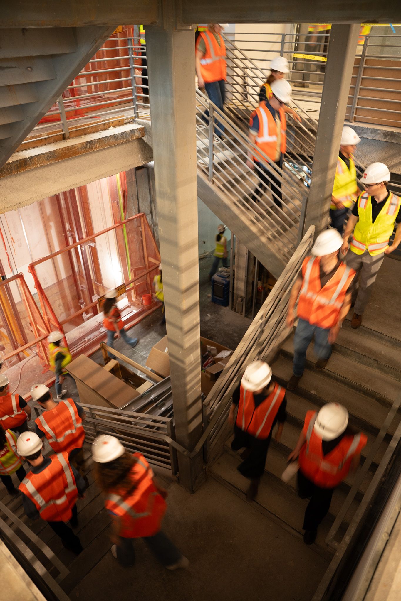 interns descend a stairway at a site visit wearing high visibility vests and hard hats