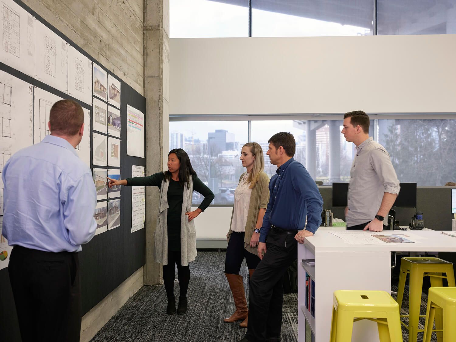 Several Mackenzie staff reviewing a set of project drawings pinned to the wall