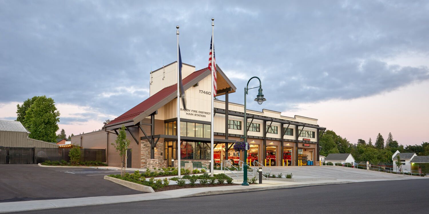 An exterior photo showing the entire fire station, with the fire truck bay doors open